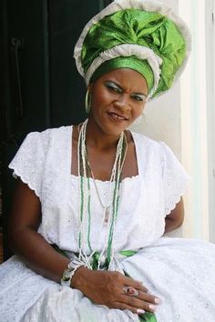 a woman wearing a green and white headdress sitting on the ground - stock image