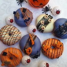 decorated doughnuts are arranged on a table with pumpkins and jack - o'- lanterns