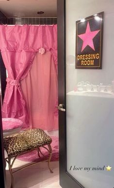 a pink bathroom with a leopard print bench and star sign on the shower stall door