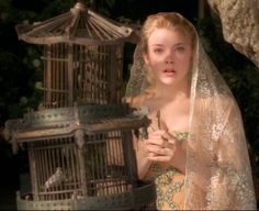 a woman in a wedding dress holding a birdcage