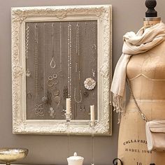 an image of a mannequin in front of a white frame with jewelry hanging on it