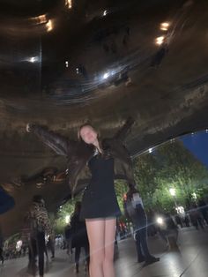 a woman is standing in front of a mirror ball with her legs spread out and arms outstretched