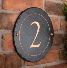 a brick wall with a sign that says 2 on it and a potted plant next to it