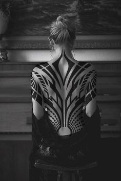 the back of a woman's body is covered in black and white art work