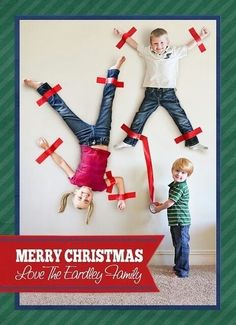 two children standing in front of a christmas card with tape taped to the wall behind them