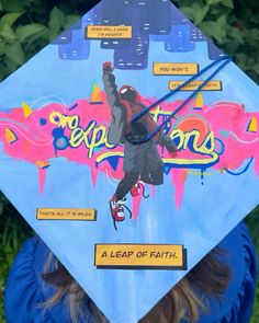 a person wearing a blue graduation cap with graffiti on it