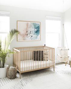 a baby's room with a crib, potted plant and pictures on the wall