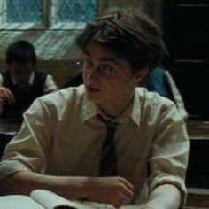 a man sitting at a desk with books in front of him and two other people behind him