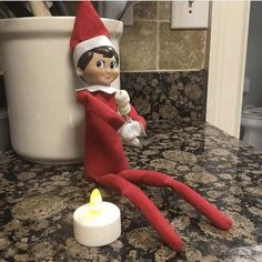 an elf is sitting on the counter next to a candle