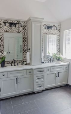 a bathroom with two sinks and mirrors on the wall next to each other in front of a window