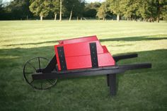 a red box sitting on top of a wooden bench in the middle of a field