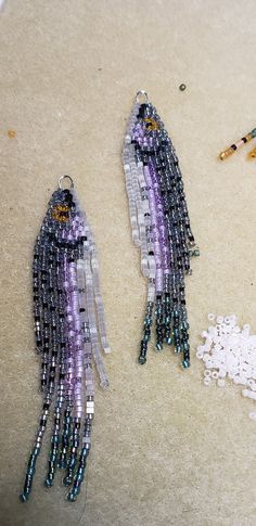 two pieces of beaded jewelry sitting on top of a table next to scissors and beads