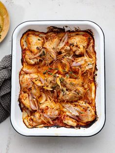 a casserole dish with chicken, onions and herbs in it on a table