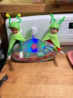 two elfs are sitting on top of a microwave