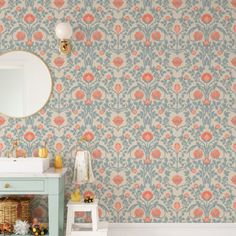 a bathroom with wallpaper and a mirror on the wall next to a blue cabinet