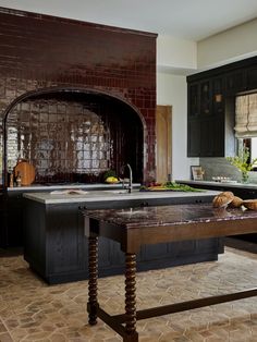 a kitchen with black cabinets and marble counter tops, along with an island in the middle