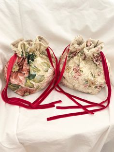 two drawstring bags sitting on top of a white sheet