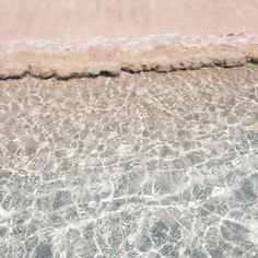 an ocean view with waves coming in from the shore and sand on the beach below