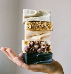 a hand holding four soap bars with different flavors