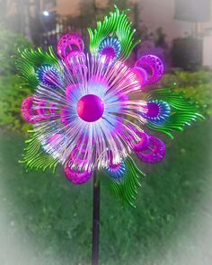 a purple and green flower sitting on top of a metal pole