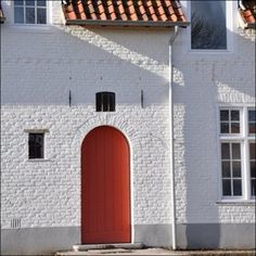 a white building with a red door and windows