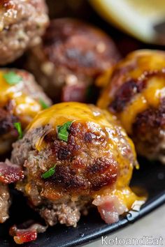 cheeseburger meatballs on a black plate with lemon wedges in the background