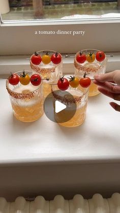 several glasses with fruit on them sitting on a window sill next to a person's hand