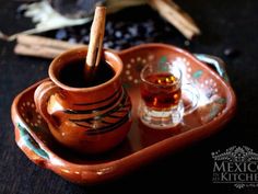 an orange tray with two cups and cinnamon sticks