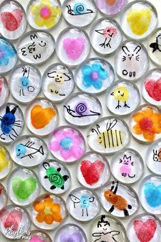 many different kinds of buttons on a white surface with words painted on them and flowers in the middle