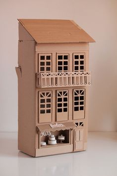 a doll house with two floors and three windows on the top floor is made out of cardboard