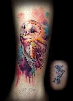 an owl tattoo on the back of a woman's lower leg with watercolor splashs