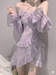 a woman in a purple dress posing for the camera with her hand up to her face