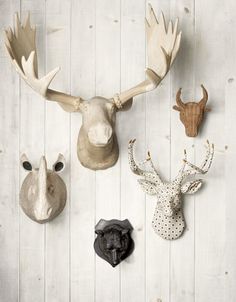 three deer head mounted to the side of a wooden wall next to other animal heads