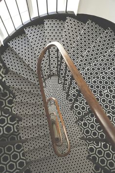 a spiral staircase with black and white tiles on the floor, along with wooden handrails