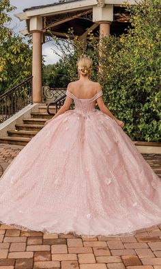 a woman in a pink ball gown standing on steps