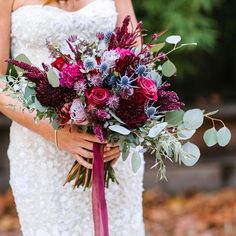 a woman holding a bouquet of flowers in her hands and wearing a white dress with purple accents