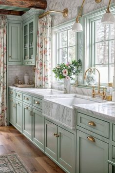 a kitchen with green cabinets, marble counter tops and gold faucet lights over the sink