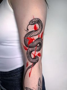 a woman's arm with a tattoo on it that has a snake and leaves