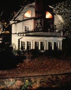 a white house with red lights on the windows and shutters is lit up at night