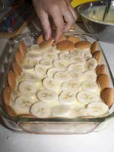 a person placing bananas on top of bread in a glass dish