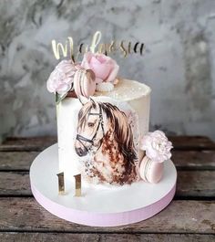 a cake decorated with a horse and flowers is on a wooden table in front of a wall