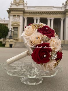 a bridal bouquet sitting on top of a glass stand in front of a building