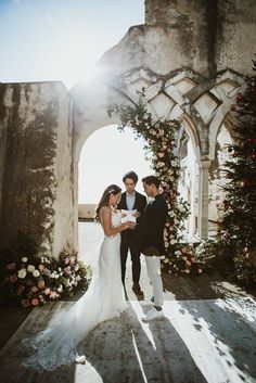 a bride and groom standing in front of an archway