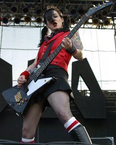 a woman in black and red outfit holding a guitar