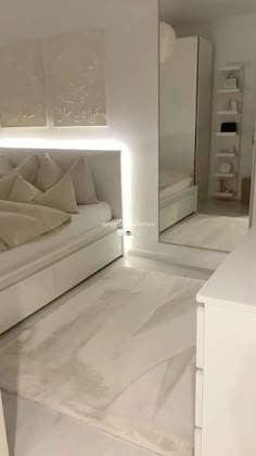 a white room with a bed, mirror and cabinets