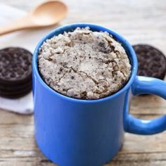 a blue mug filled with cookies on top of a wooden table