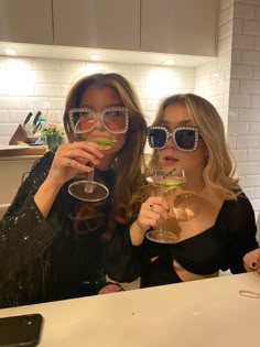 two women wearing sunglasses holding up wine glasses