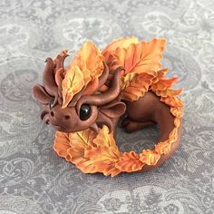 a figurine of a dragon with orange leaves on it's head and tail