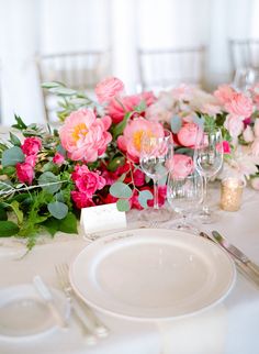 the table is set with pink flowers and place settings for dinner guests to sit at