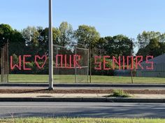 a fence that has been decorated with pink letters on it and the words we are your seniors written in red